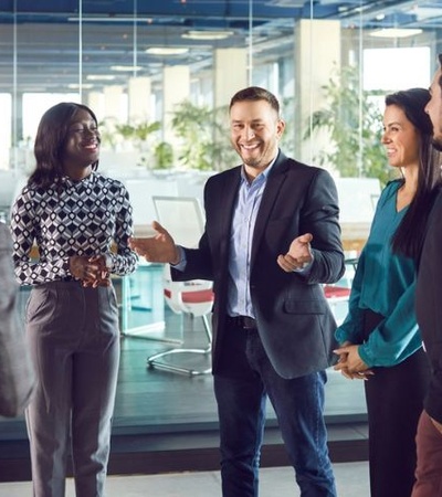 A group of professionals engaged in a lively conversation in a modern office setting.