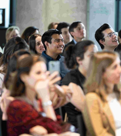 A diverse group of people smiling and engaged in a conversation during an event.