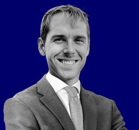 A smiling man in a suit against a blue background