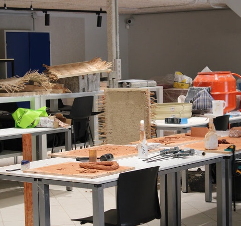 A workspace with various tools and materials scattered across tables and shelves.
