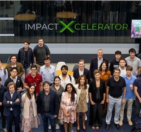 A group of people gathered in front of a sign that reads 'IMPACT XCELERATOR'.