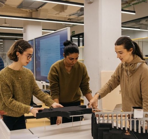 Three individuals are collaborating on a project in a modern workspace.