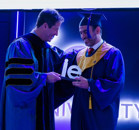 A graduate receiving a diploma from a faculty member during a ceremony.