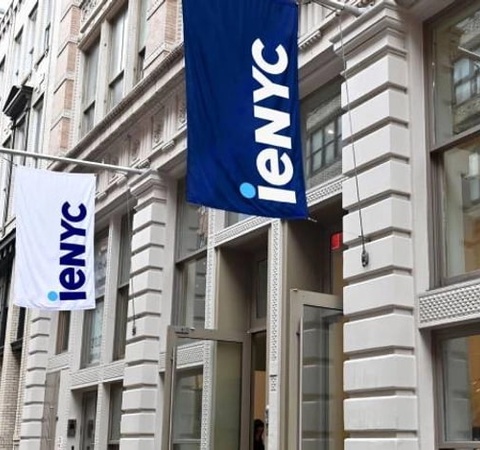 A street view of a building with flags displaying the logo of 'ieNYC'.