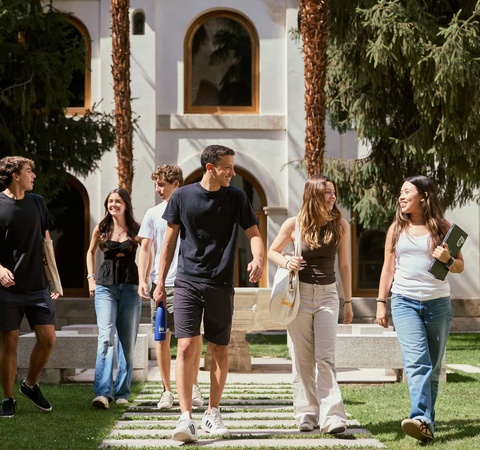 A group of young people walking together in a lush garden setting.