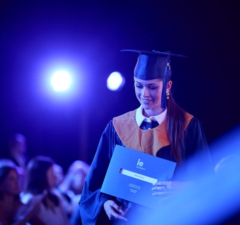 A graduate receiving their diploma on stage during a ceremony.