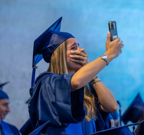 A joyful graduate taking a selfie while celebrating her achievement.