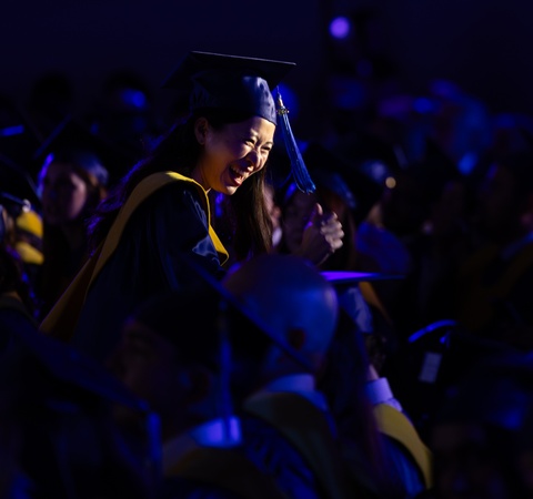A graduate joyfully celebrates during a commencement ceremony.