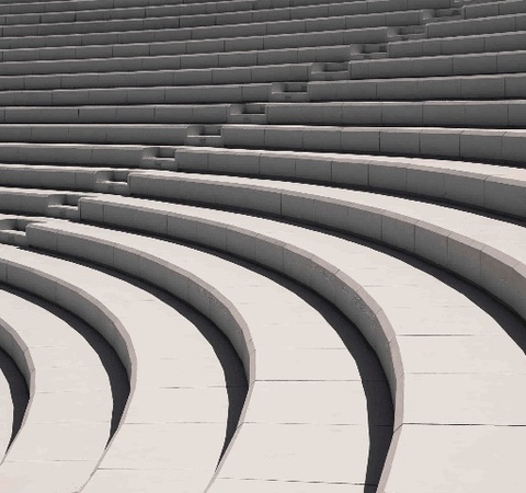 A grayscale image of curved concrete steps forming an open-air amphitheater.