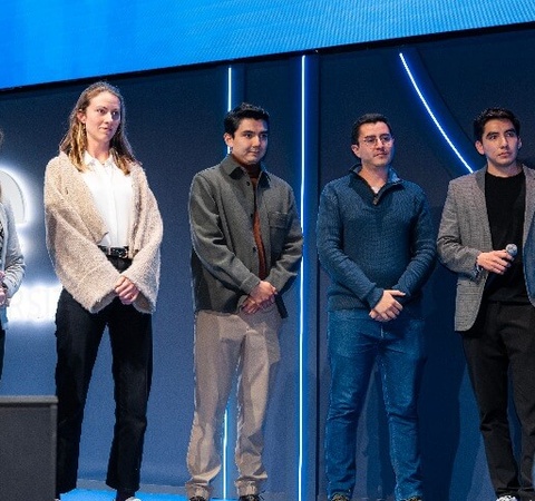 Five people standing on stage at a conference, facing the audience.