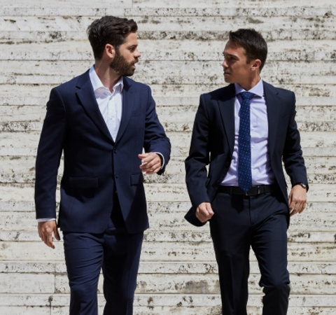 Two men in suits walking down stairs while engaged in conversation.