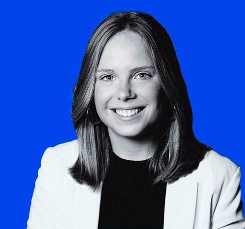 A portrait of a smiling woman with blonde hair against a solid blue background.