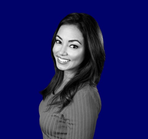 A black and white photo of a smiling woman with a bright blue background.