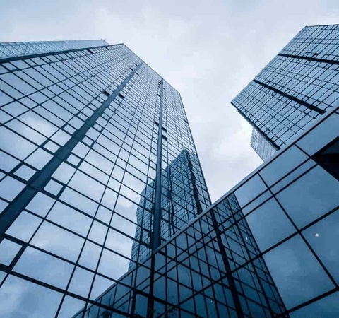 Low angle view of modern glass skyscrapers with reflections of clouds.