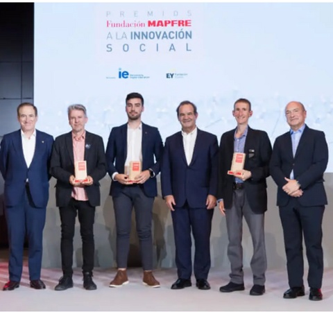 A group of six men standing on a stage holding awards at a social innovation event.