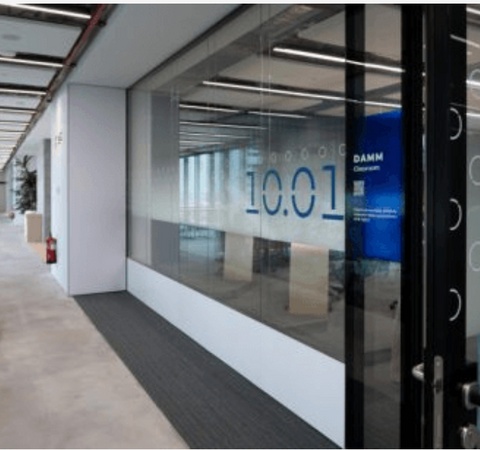 A modern office space with a glass meeting room displaying the time 10:01.