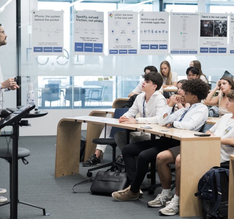 A teacher is giving a presentation to a classroom of students who are attentively listening.