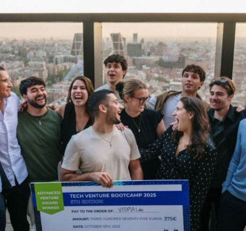 A group of people celebrating together while holding a large check for a tech venture bootcamp.