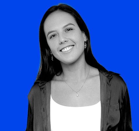 A smiling young woman with long hair against a vivid blue background