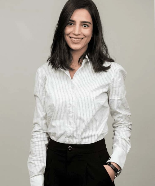 A woman in a white shirt and black pants smiling at the camera in a professional setting.