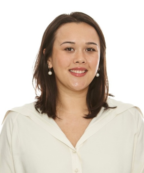 A portrait of a smiling woman wearing a white blouse and pearl earrings against a white background.