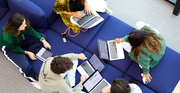 A group of students collaborating on laptops in a casual setting.