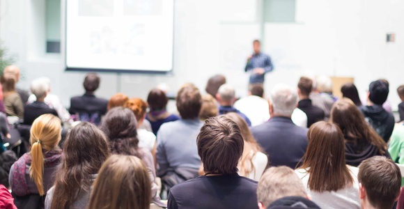 A crowd of people attending a presentation in a lecture hall.