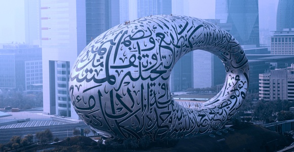 A large, futuristic sculpture featuring intricate calligraphy in an urban setting.