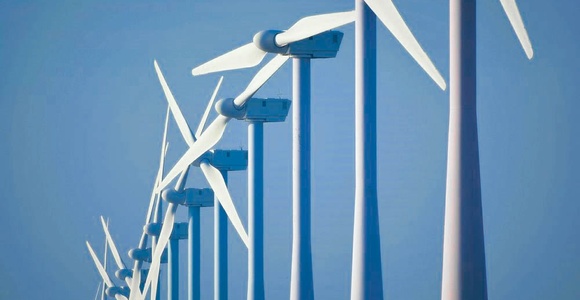 A line of wind turbines against a clear blue sky.