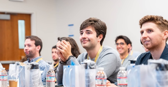 Group of people sitting in a classroom, listening attentively.