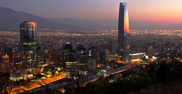 A panoramic view of a city skyline at sunset, featuring modern skyscrapers and a glowing horizon.
