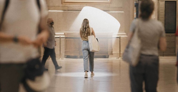 A woman walks through a busy hall, surrounded by other people.