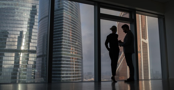 A couple is silhouetted against large urban skyscrapers.