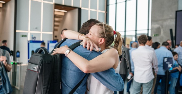A joyful reunion between two people embracing in a lively environment.