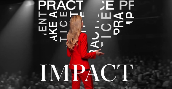 A woman in a red suit stands on stage, facing an audience with the word 'IMPACT' highlighted in front of her.