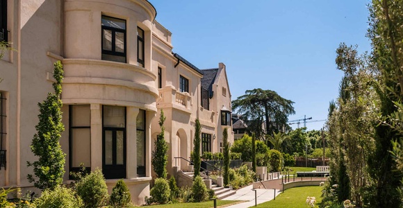 A luxurious villa surrounded by a beautifully landscaped garden under clear blue skies.