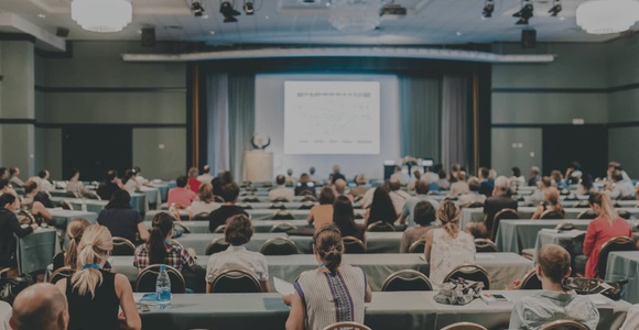 A large audience attending a presentation in a conference room.