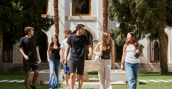 A group of young people walking together in a lush garden setting.