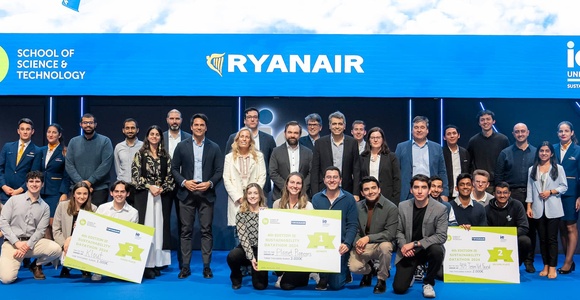 A group of people, including business professionals and students, posing with large checks at an event sponsored by Ryanair and IE University.