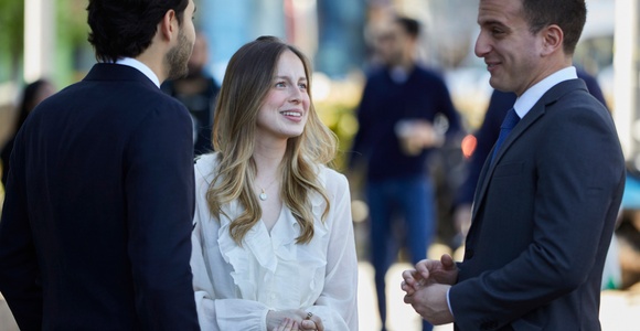 A group of three people are engaging in a conversation outdoors.