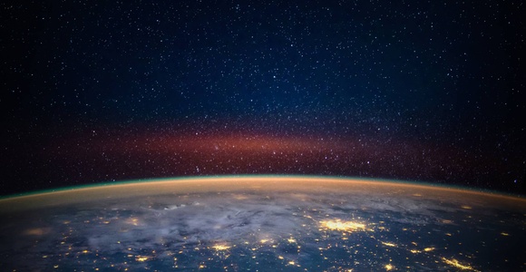 A breathtaking view of Earth from space, showcasing a dark sky filled with stars and the planet's illuminated surface.