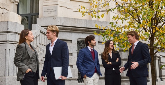 A group of young professionals engaged in a discussion outside a building.
