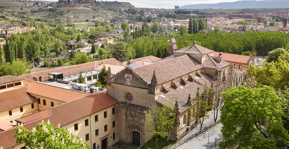 A scenic view of a historical building surrounded by greenery and hills.