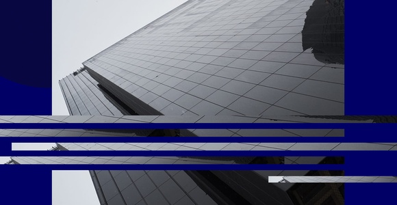 A modern skyscraper with reflective glass panels under a cloudy sky.