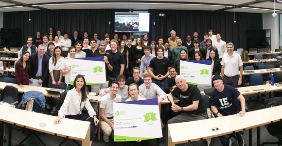 A group of people posing in a classroom environment, holding certificates and smiling at the camera.