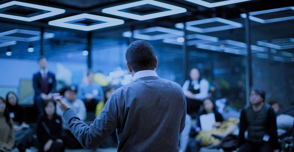 A man is giving a presentation to an attentive audience in a modern office setting.