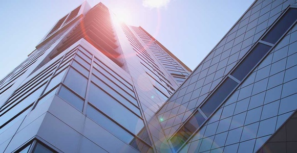 Low angle view of a modern skyscraper with sun flare.