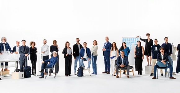 A diverse group of professionals standing and sitting together in a bright, minimalistic studio.