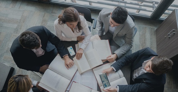 A group of professionals reviewing documents around a table.