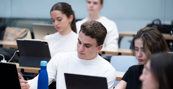 Students using laptops in a university classroom.